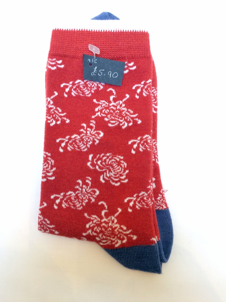 Tomato red socks with a pattern of large white flowers. Denim blue heels and toes. Thin white stripe at the top of the self-coloured cuff