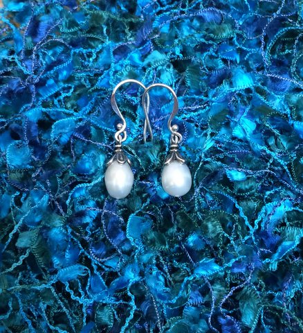 Hook earrings. A pearl is clasped at the top by chased leaves of silver